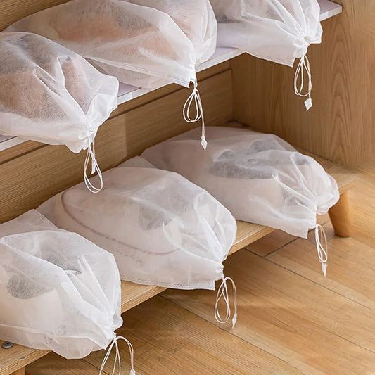 Drawstring shoe bags for travel and packing on a wooden shelf, organized for luggage.